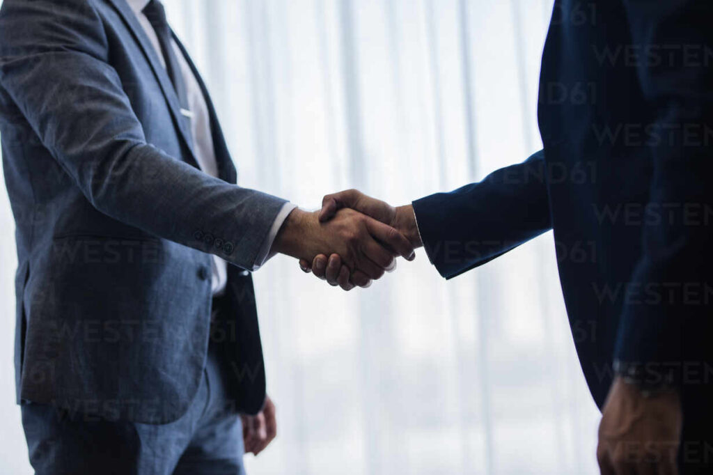close up of two businessmen handshaking after good deal. business people shaking hands and finishing up a meeting in office.
